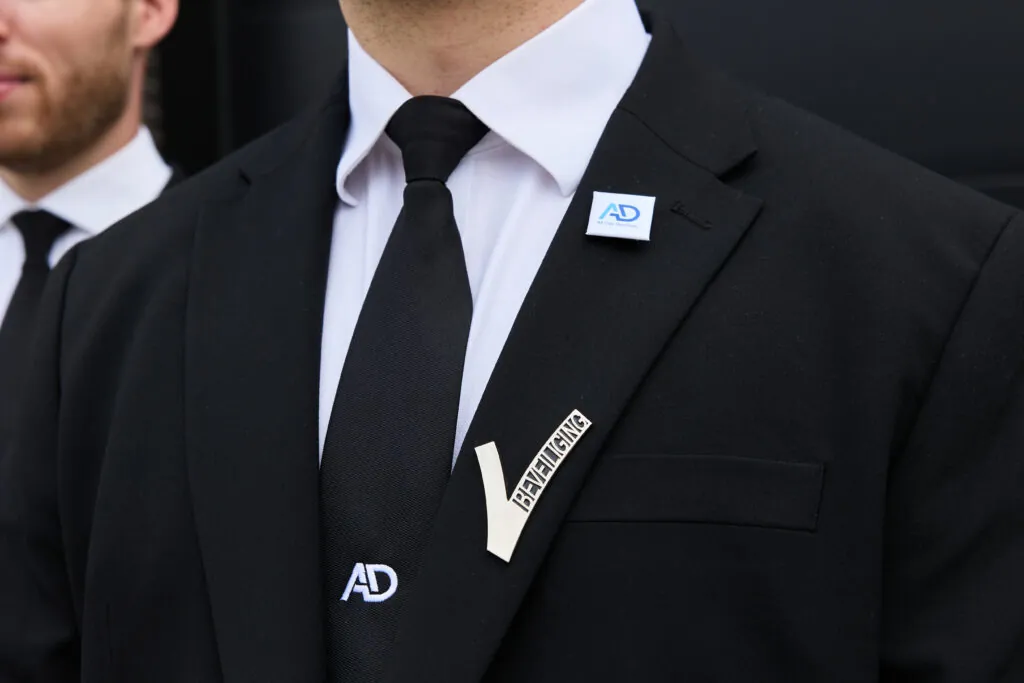 Persoonsbeveiligers van All Day Services in pak met legitimatie zichtbaar op de revers